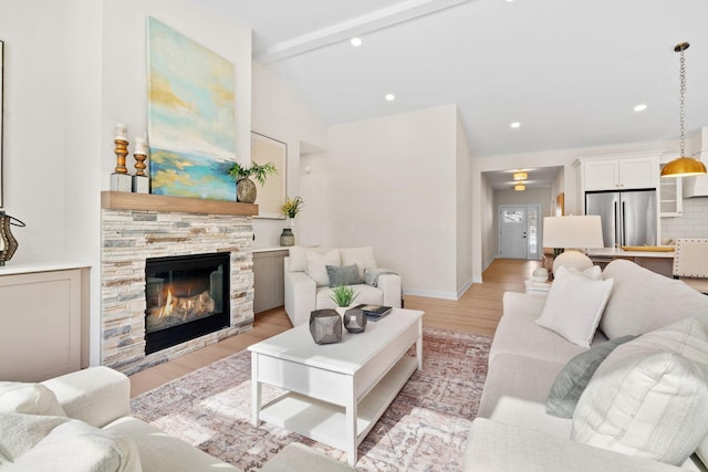 living room with baseboards, lofted ceiling with beams, a stone fireplace, recessed lighting, and light wood-style floors