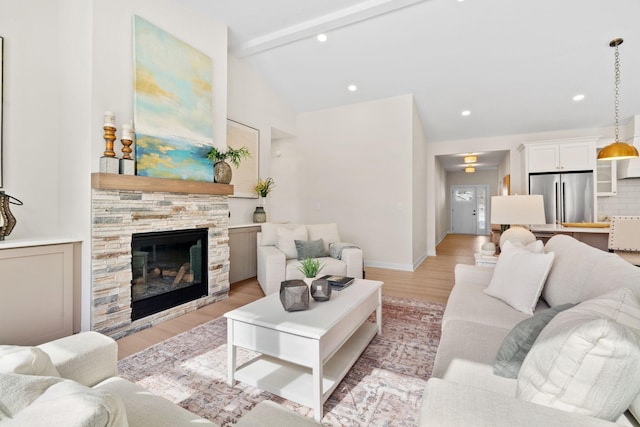 living area featuring baseboards, vaulted ceiling with beams, a fireplace, recessed lighting, and light wood-style floors