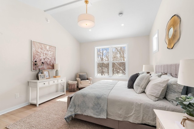 bedroom with light wood finished floors, baseboards, and lofted ceiling