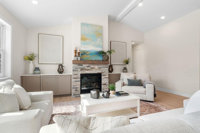 living area with baseboards, lofted ceiling with beams, a stone fireplace, recessed lighting, and light wood-style flooring