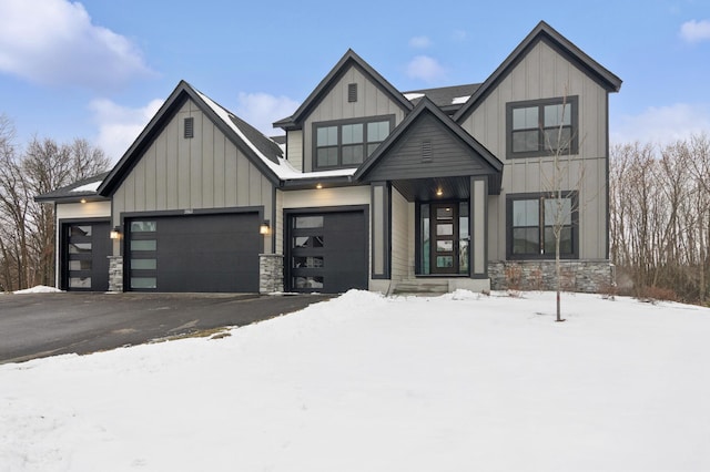 modern inspired farmhouse with a garage, stone siding, board and batten siding, and driveway