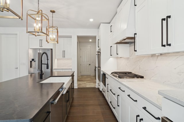 kitchen featuring premium range hood, dark wood-style flooring, appliances with stainless steel finishes, white cabinetry, and backsplash