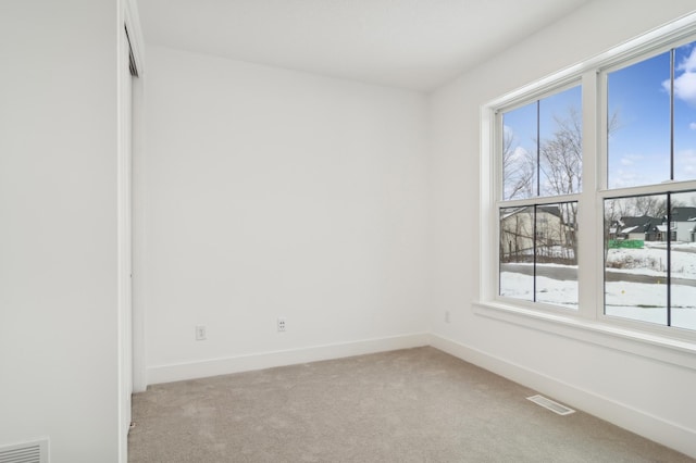 empty room featuring visible vents, light colored carpet, and baseboards