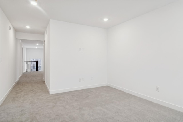 spare room featuring recessed lighting, baseboards, and light colored carpet