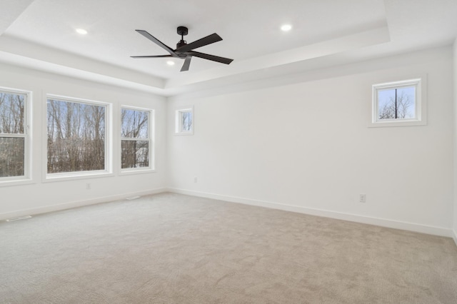 spare room featuring recessed lighting, a tray ceiling, baseboards, and light colored carpet