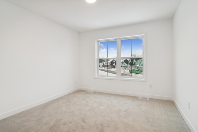 unfurnished room featuring light carpet, visible vents, and baseboards