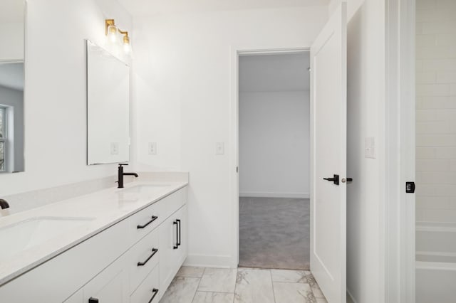 bathroom with double vanity, a bathing tub, marble finish floor, and a sink