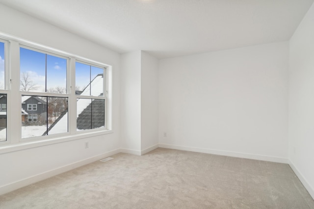 empty room with visible vents, light colored carpet, and baseboards