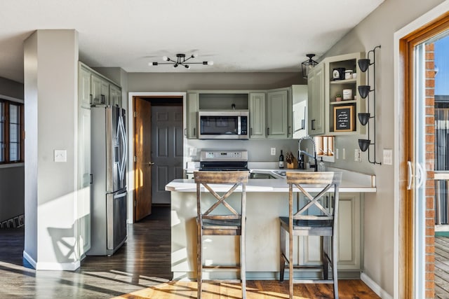 kitchen with open shelves, green cabinets, appliances with stainless steel finishes, and a peninsula