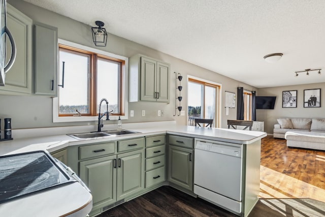 kitchen with dark wood-type flooring, a sink, a peninsula, green cabinets, and dishwasher