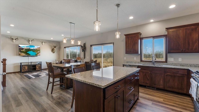 kitchen featuring recessed lighting, dark wood-style flooring, a sink, hanging light fixtures, and a center island