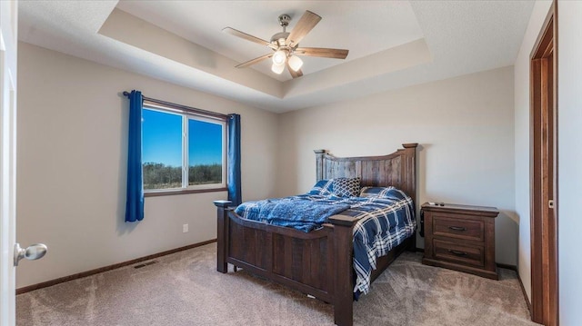 carpeted bedroom featuring a ceiling fan, a raised ceiling, baseboards, and visible vents