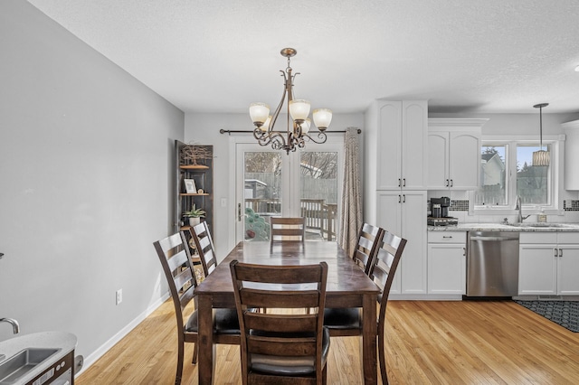 dining room with a notable chandelier, a textured ceiling, light wood-type flooring, and baseboards