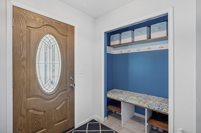 mudroom featuring tile patterned floors, a textured ceiling, and baseboards