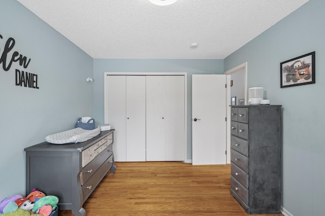 bedroom featuring light wood-type flooring, a closet, and a textured ceiling