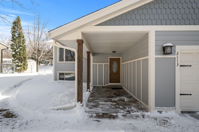 snow covered property entrance with a garage