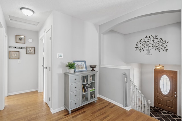 foyer entrance with baseboards, a textured ceiling, and wood finished floors