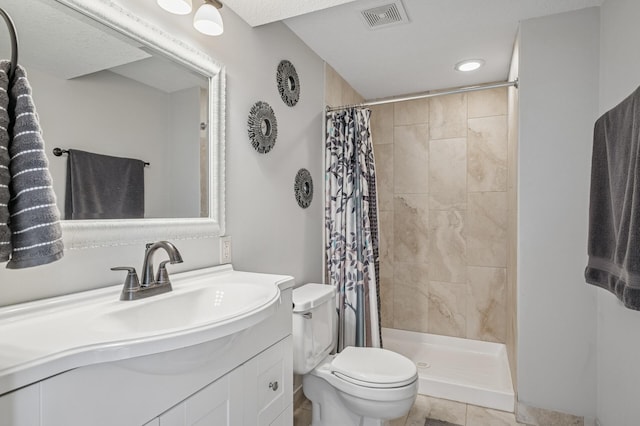 full bathroom with a tile shower, visible vents, toilet, and vanity