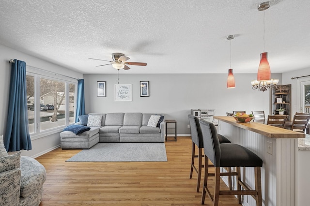 living room featuring light wood-type flooring, baseboards, and a textured ceiling