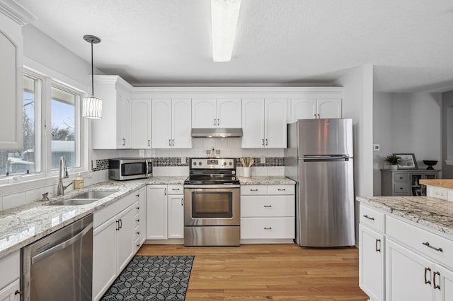 kitchen with under cabinet range hood, a sink, white cabinetry, stainless steel appliances, and light wood-style floors