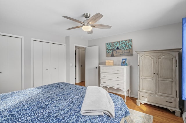 bedroom with light wood finished floors, ceiling fan, and multiple closets