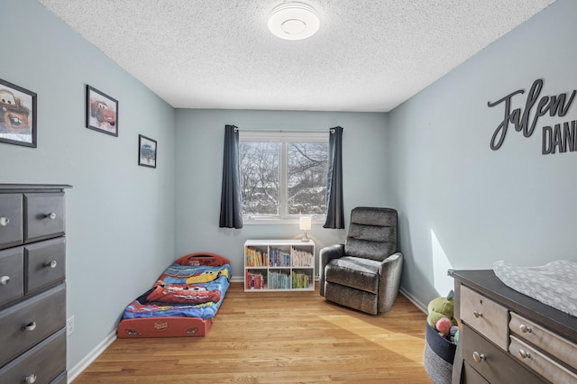 bedroom featuring light wood-style flooring, a textured ceiling, and baseboards