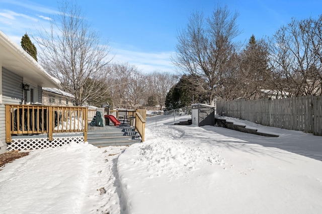 snowy yard featuring a wooden deck and fence