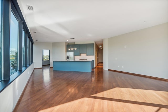 unfurnished living room featuring visible vents, baseboards, and dark wood-style flooring