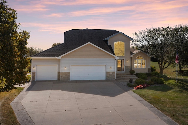 traditional-style home with stone siding, driveway, an attached garage, and a front yard