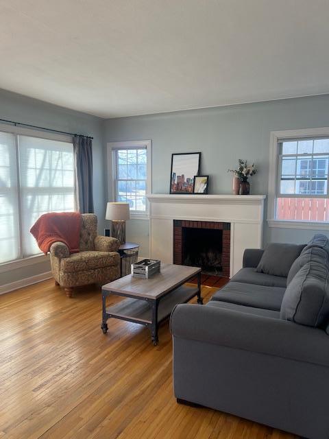 living room with a brick fireplace and light wood-style floors