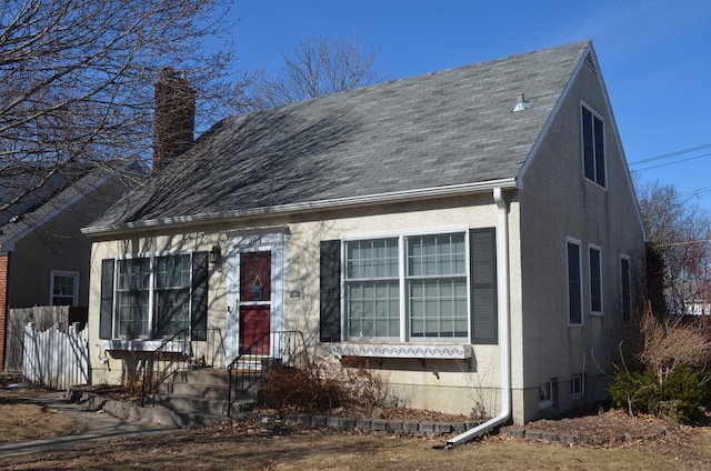 view of front of home featuring stucco siding, a chimney, and a shingled roof