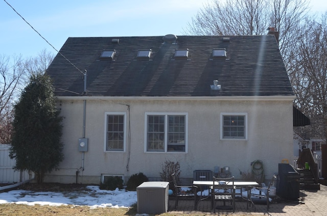 rear view of house with a patio area, stucco siding, and a chimney