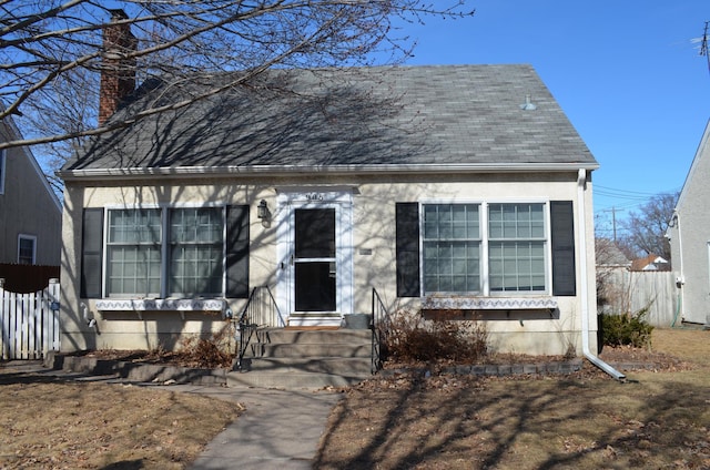 new england style home featuring entry steps, a chimney, and fence