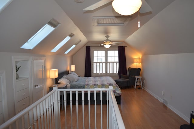 bedroom featuring visible vents, a ceiling fan, wood finished floors, baseboards, and vaulted ceiling