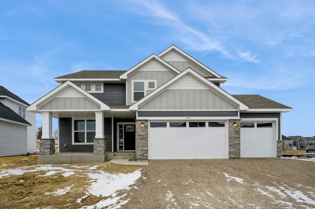 craftsman-style house featuring board and batten siding, gravel driveway, a porch, roof with shingles, and an attached garage