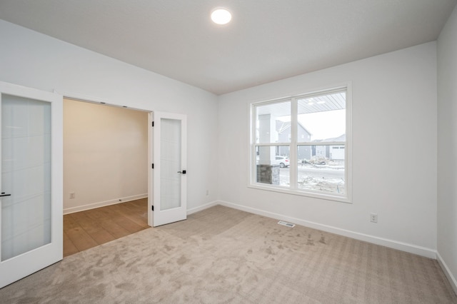 unfurnished bedroom featuring visible vents, french doors, carpet, baseboards, and vaulted ceiling