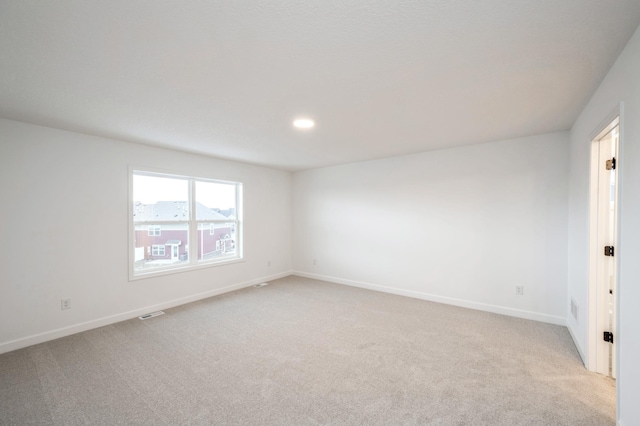 spare room featuring light colored carpet and baseboards