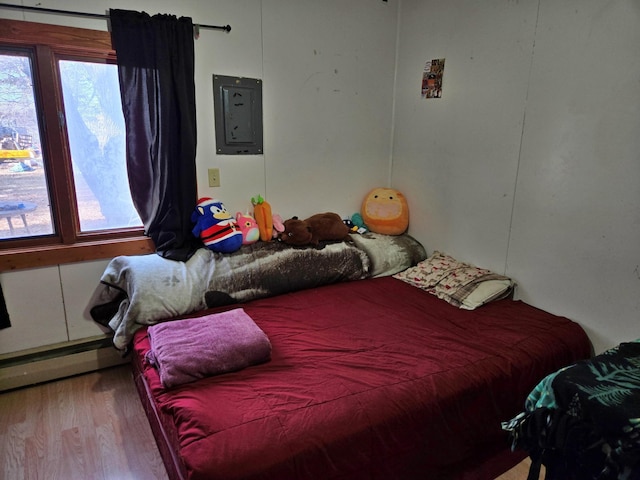 bedroom featuring electric panel, baseboard heating, and wood finished floors