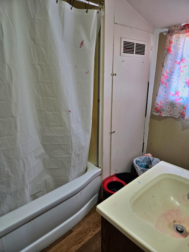 bathroom with wood finished floors, visible vents, lofted ceiling, a sink, and shower / tub combo