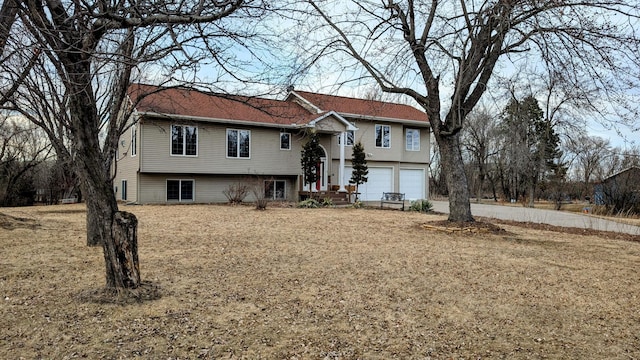 raised ranch featuring an attached garage and driveway