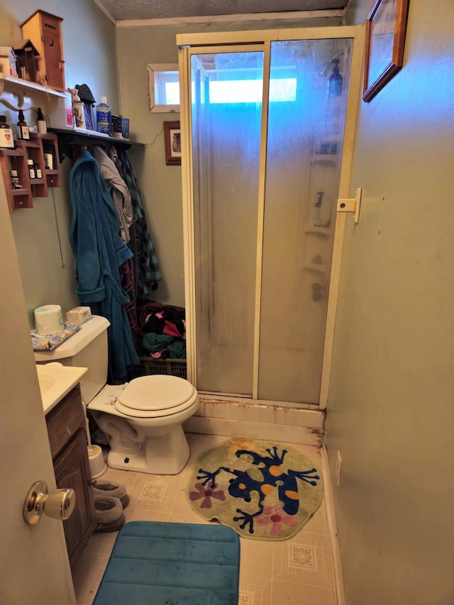 bathroom featuring tile patterned floors, toilet, a stall shower, and vanity