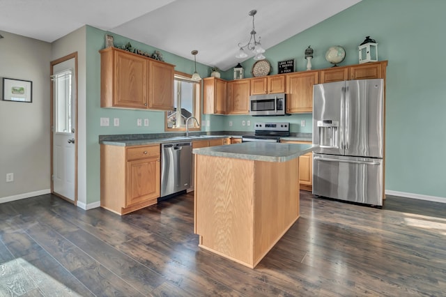 kitchen with dark wood-type flooring, pendant lighting, vaulted ceiling, stainless steel appliances, and a sink