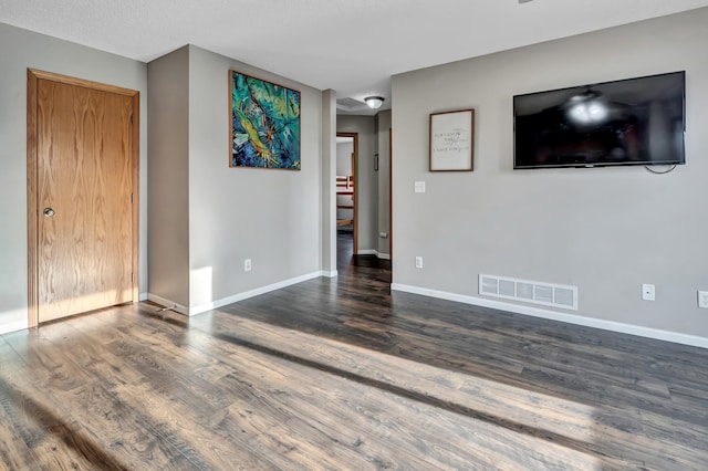 unfurnished living room featuring visible vents, baseboards, and wood finished floors