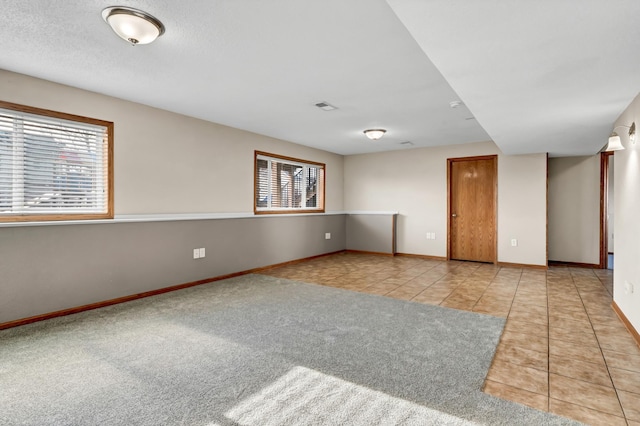 tiled empty room featuring carpet, visible vents, and baseboards