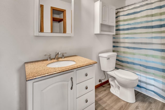 bathroom with vanity, toilet, wood finished floors, and baseboards