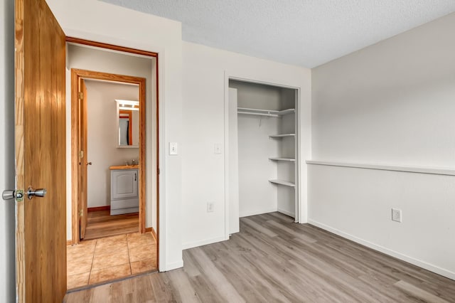 unfurnished bedroom with a sink, a textured ceiling, wood finished floors, a closet, and baseboards