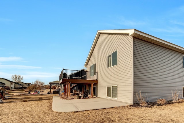 back of property featuring a deck, stairway, and a patio