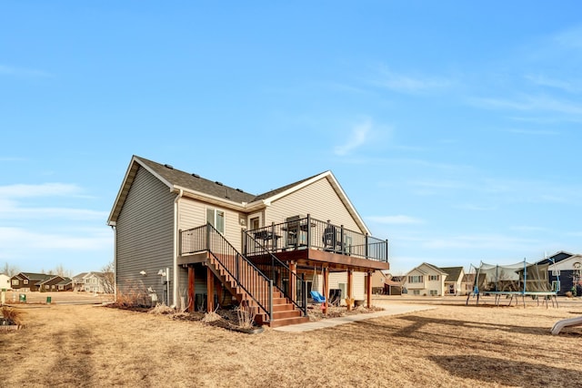 back of property with stairway, a trampoline, and a wooden deck