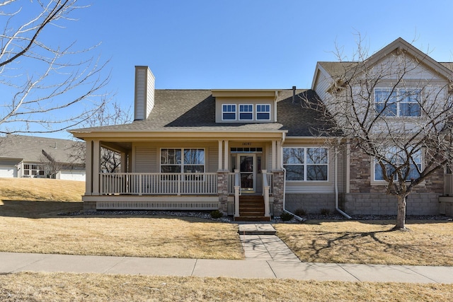 view of front of property with covered porch, a chimney, and a shingled roof