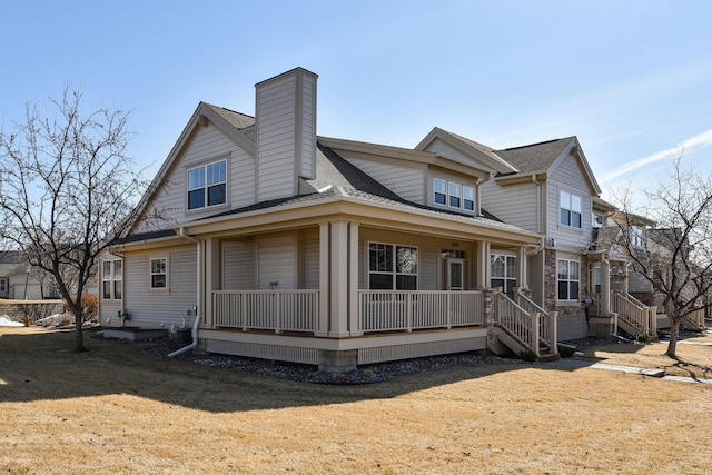 view of front of home with a chimney, a porch, a shingled roof, and a front yard